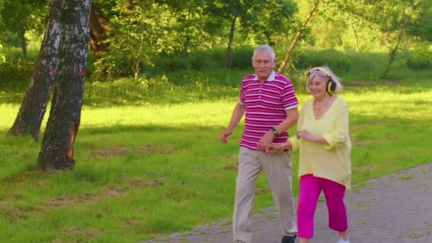 Senioren stijlvol paar familie grootvader dansen, wandelen luisteren muziek in de zomer park — Stockvideo