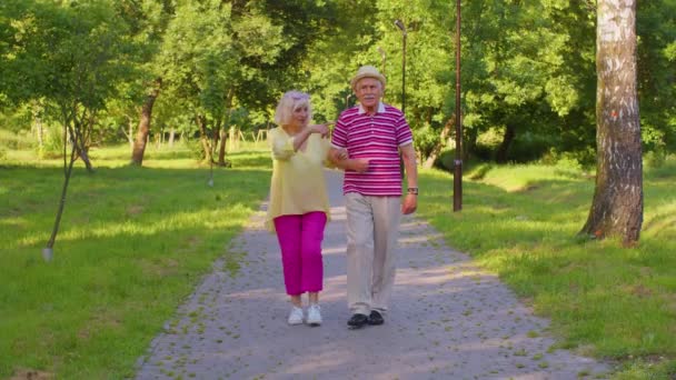 Senioren stijlvolle gepensioneerden paar grootvader wandelen, genieten van tijd samen in park — Stockvideo