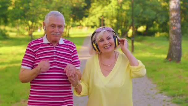 Літня стильна пара сімейна бабуся, дідусь танцює прогулянки, слухаючи музику в літньому парку — стокове відео