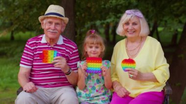 Son sınıfların şık çifti büyük anne ve büyük baba ve torun stres karşıtı pop it oyuncak oyunu oynuyorlar