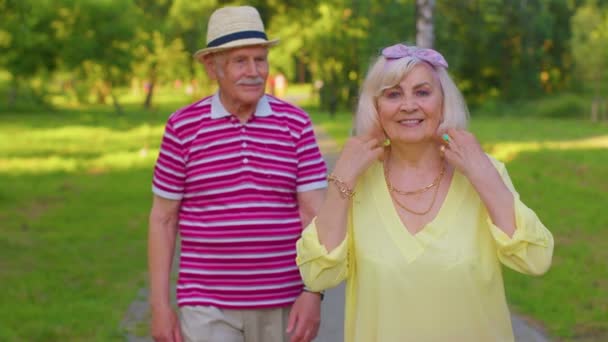 Actieve senior opa gepensioneerde lopen naar stijlvolle oma en het maken van een kus in de zomer park — Stockvideo