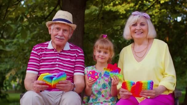 Starszy dziadek babcia z wnuczka gospodarstwa anty-stres pop to zabawka gry w parku — Wideo stockowe
