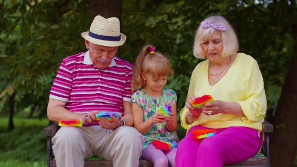 Sorrindo avô avó sênior com neta jogando espremendo jogo de brinquedos anti-stress — Vídeo de Stock