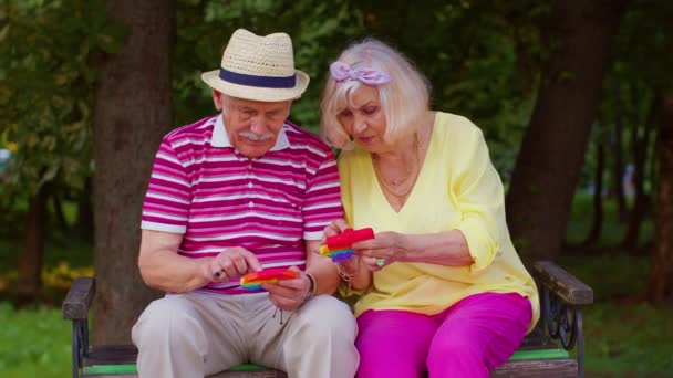 Старшая стильная пара бабушка дедушка сжимая анти-стресс толчок поп популярной игрушечной игры — стоковое видео
