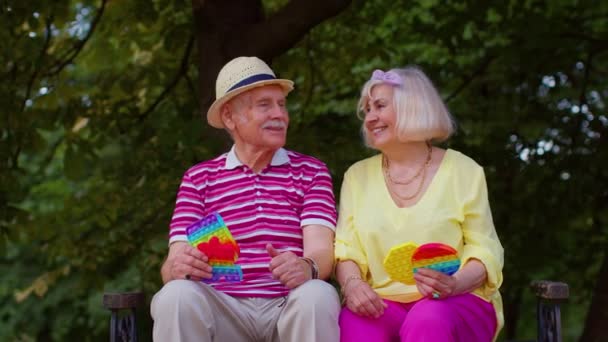 Senior stylish grandmother grandfather showing squeezing anti-stress push pop it popular toy game — Stockvideo