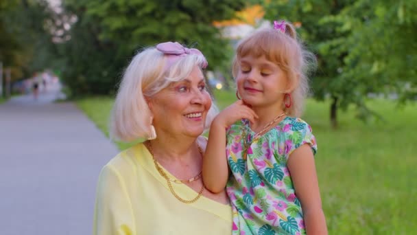 Little granddaughter child embracing kissing with her grandmother in park, happy family relationship — Stockvideo
