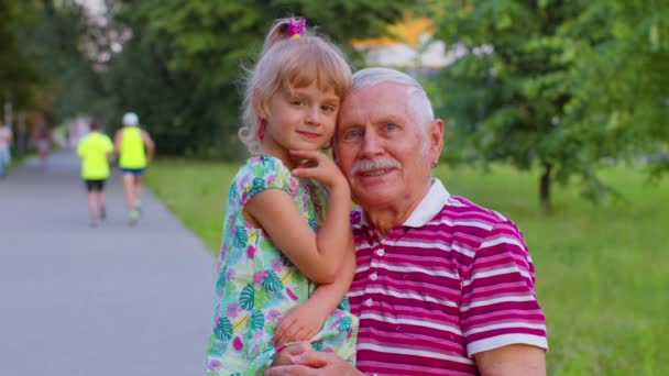 Pequena neta criança abraçando beijos com seu avô no parque, relacionamento familiar feliz — Vídeo de Stock
