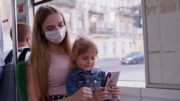 Mujer cansada y soñolienta con su hija yendo a casa en autobús después de un duro día de trabajo, el niño juega en el teléfono inteligente — Vídeo de stock