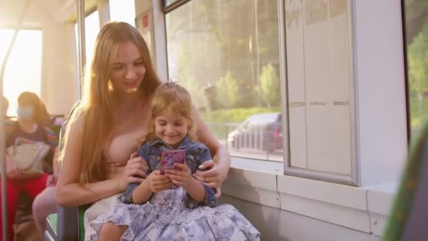 Mujer e hija usando la aplicación de red social de Internet de teléfono móvil, viajando en autobús o tranvía — Vídeos de Stock