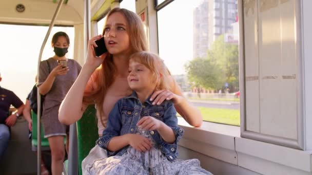 Родительская мать разговаривает по мобильному телефону, игнорирует маленького ребенка дочь, сидя в общественном трамвае — стоковое видео