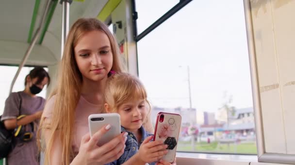 Дитя девочка с мамой с помощью смартфона чата смс в социальных сетях, автобусе общественного транспорта, трамвае — стоковое видео