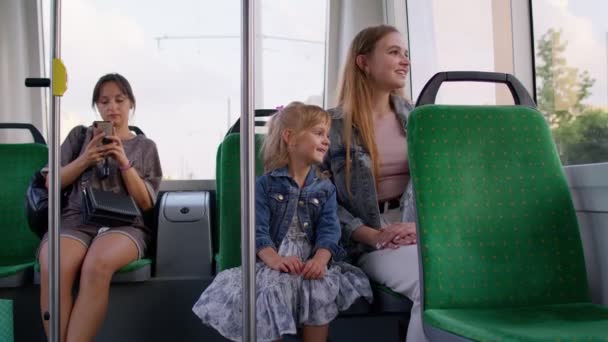 Familjeåkattraktioner i kollektivtrafiken, kvinna med liten flicka sitter tillsammans och tittar ut genom fönstret spårvagn — Stockvideo