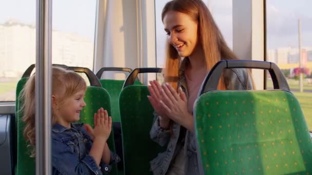 Paseos en familia en tranvía de transporte público, la madre con la niña se sientan juntos y juegan juego aplaudiendo las manos — Vídeo de stock