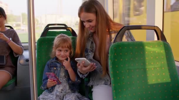 Niña con madre usando la aplicación de red social de Internet de teléfono móvil mientras viaja en autobús — Vídeo de stock