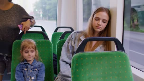 Wyczerpana matka zasypia i przegapiła przystanek tramwajowy, córeczka budzi zmęczoną śpiącą kobietę — Wideo stockowe