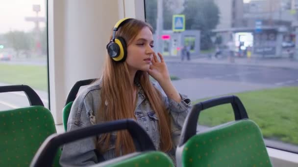 Junge Frau mit Kopfhörern hört Musik, entspannen Sie sich beim Tanzen, während Sie mit dem Bus in die Stadt fahren — Stockvideo