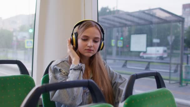 Молодая женщина в наушниках слушает музыку, весело расслабиться танцы во время путешествия на автобусе в город — стоковое видео