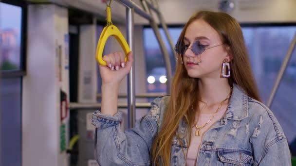 Attraktiv ung kvinna passagerare ridning på offentlig modern buss eller spårvagn transport, tittar ut genom fönstret — Stockvideo