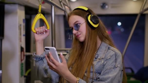Jeune fille utilisant un téléphone mobile internet réseau social écouter de la musique voyageant en bus de la ville publique — Video