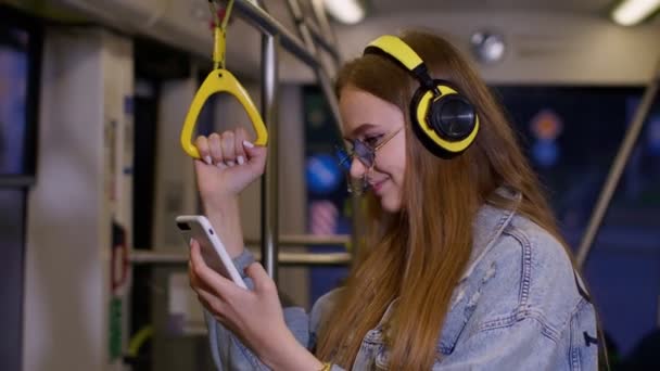 Giovane donna che indossa cuffie ascoltare musica, divertente relax ballare mentre si viaggia in autobus per la città — Video Stock