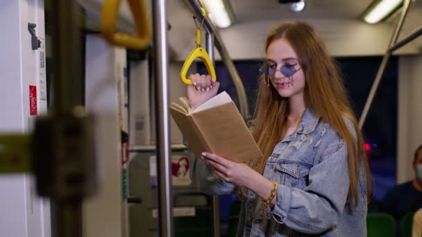 Retrato de atractiva mujer adulta joven permanecer en el tren subterráneo vacío y la lectura de libro interesante — Vídeo de stock