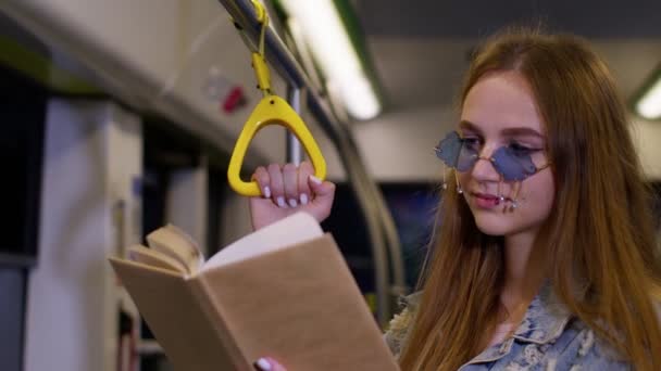 Portrét atraktivní mladé dospělé ženy pobyt v prázdném vlaku metra a čtení zajímavé knihy — Stock video