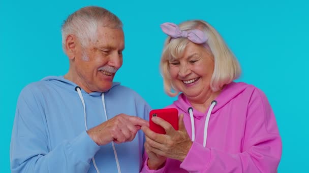 高齢の祖父母の年金受給者は、携帯電話を使って新しいポスト、ブラウジング、オンラインショッピングを入力します。 — ストック動画