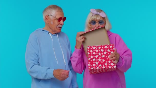 Старший дедушка бабушка разворачивая подарок, выражая разочарование, не нравится плохой подарок — стоковое видео