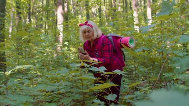 Anciana jubilada abuela aventurera explorando árboles forestales, plantas con teléfono celular móvil — Vídeo de stock