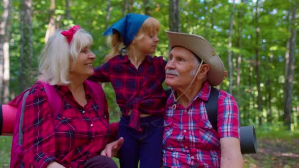 Mormor farfar och barn flicka familj vandrare turister sitter i trä, kramas, kyssas — Stockvideo