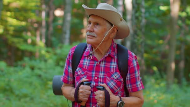 Старший старий кавказький туристичний дідусь навчає скандинавську ходьбу з пішоходами в лісі. — стокове відео