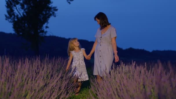 Очаровательная маленькая милая дочь ребенок ходить с матерью в лавандовом поле, играть с цветами — стоковое видео