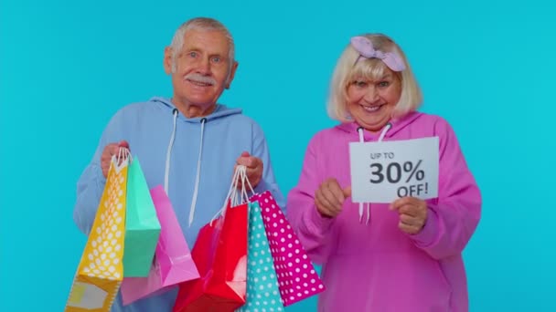 Senior-Großeltern zeigen Einkaufstüten und bis zu 30 Prozent Rabatt auf Werbebanner, Black Friday, Feiertag — Stockvideo