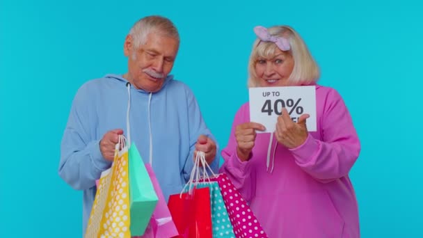 Kakek nenek senior yang menunjukkan tas belanja dan poster Up To 40 Percent Off, Liburan Jumat Hitam — Stok Video