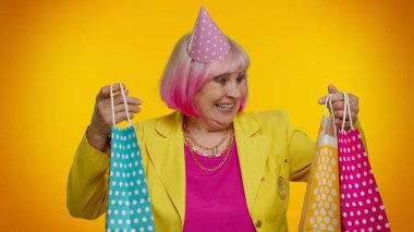 Alışveriş torbaları, reklam indirimleri gösteren yaşlı bir kadın. Düşük fiyatlarla şaşkın şaşkın bakıyor.