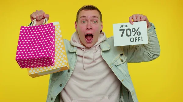 Alegre teen homem mostrando compras sacos e até 70 por cento fora inscrições banner, Black Friday — Fotografia de Stock