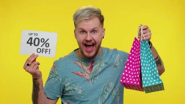 Fröhlicher Touristenmann zeigt Einkaufstüten und bis zu 40 Prozent Rabatt auf Aufschriften am Black Friday — Stockfoto