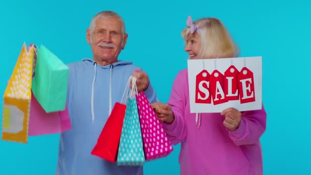 Les grands-parents seniors tiennent des sacs à provisions, texte de bannière d'inscription de vente, rabais de prix de publicité — Video