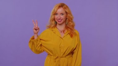 Güzel bir gülümseme gösteren kız zafer işareti gösteriyor, başarı ve kazanmayı umuyor, barış jesti yapıyor.