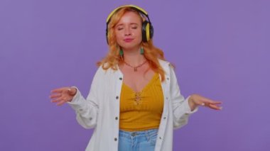 Neşeli çekici kız kulaklıkla müzik dinliyor ve dans edip eğleniyor.