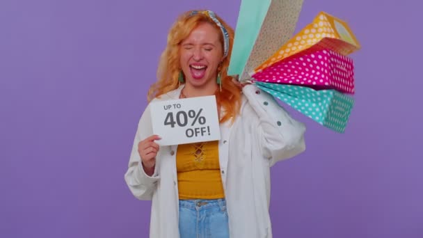 Vidám vörös hajú lány bemutató bevásárló táskák, akár 40 százalékos Off feliratok banner, Fekete péntek — Stock videók