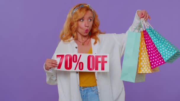 Vidám vörös hajú lány bemutató bevásárló táskák, akár 70 százalékos Off feliratok banner, Fekete péntek — Stock videók