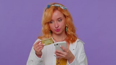 Para transfer ederken kredi kartı ve akıllı telefon kullanan bir kadın, internetten alışveriş yapıyor.