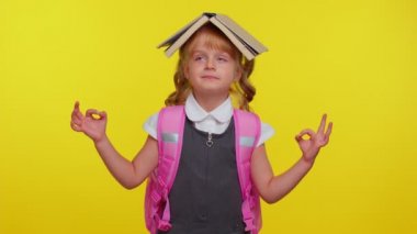 Okul üniformalı genç kız kafaya kitap takıyor, meditasyon yapıyor, konsantre düşüncelerle rahatlıyor.