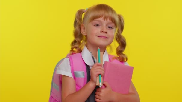 Alegre colegiala divertida con libros vestidos de uniforme lleva mochila sonriendo mirando a la cámara — Vídeo de stock