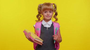 Atkuyruklu, üniformalı, sarı arka planda gülümseyen komik, pozitif bir ilkokul çocuğu.