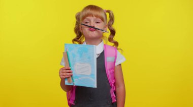 Komik, neşeli ilkokul öğrencisi kız kalemle maskaralık yapıyor.