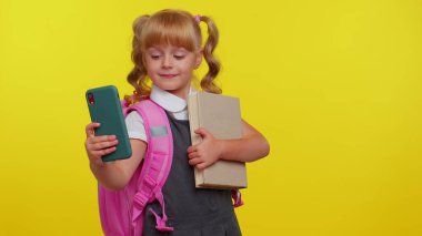 Okul kızı blog yazarı üniformalı, selfie çekiyor, sosyal medya için cep telefonuyla video kaydediyor.