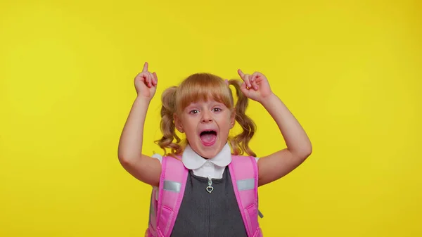 Niña de la escuela en uniforme mostrando los pulgares hacia arriba, apuntando hacia arriba en el espacio de copia de contenido promocional —  Fotos de Stock