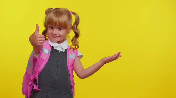 Sonriente niña linda colegiala con mochila mirando el espacio de copia para el contenido promocional de la mano — Foto de Stock